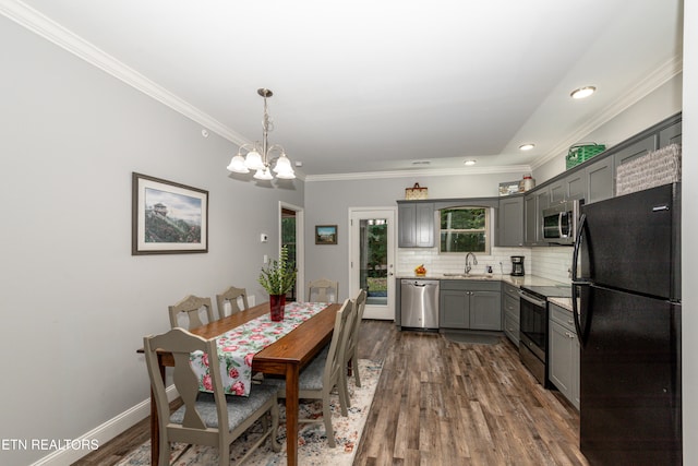 dining space featuring dark wood-type flooring, crown molding, sink, and an inviting chandelier