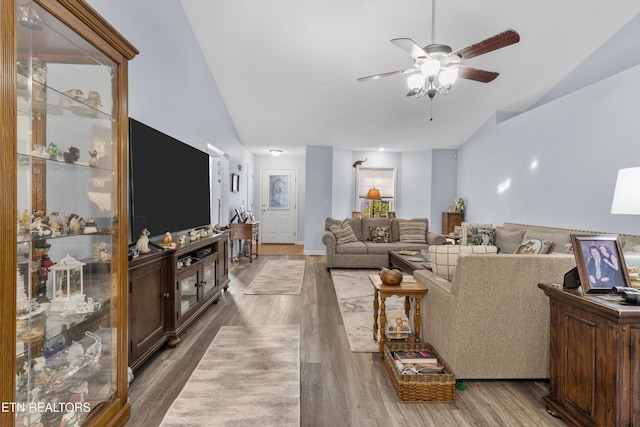 living room featuring ceiling fan, wood-type flooring, and vaulted ceiling