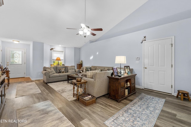 living room with light hardwood / wood-style flooring, ceiling fan, and vaulted ceiling