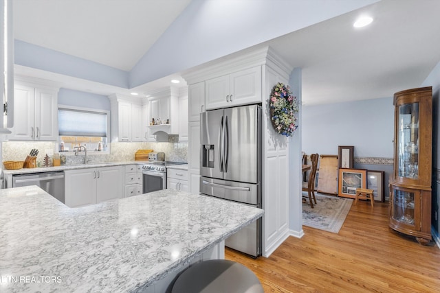 kitchen featuring light hardwood / wood-style flooring, white cabinetry, stainless steel appliances, and lofted ceiling