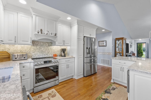 kitchen with stainless steel appliances, light stone countertops, white cabinets, light hardwood / wood-style floors, and tasteful backsplash