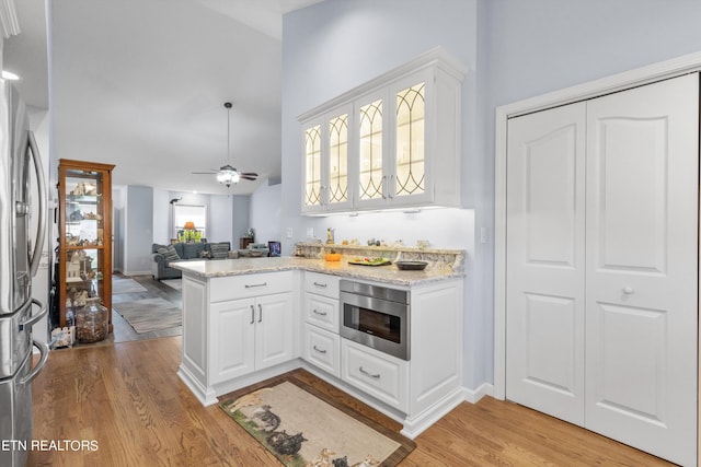 kitchen with kitchen peninsula, ceiling fan, appliances with stainless steel finishes, white cabinetry, and light hardwood / wood-style floors