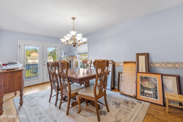 dining area with french doors, light hardwood / wood-style flooring, and an inviting chandelier