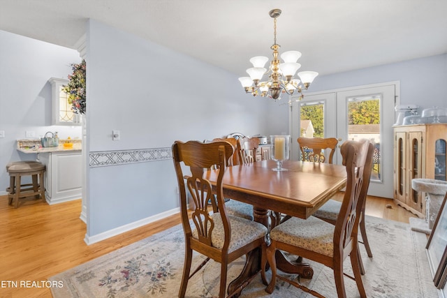 dining room featuring french doors, light hardwood / wood-style flooring, and an inviting chandelier