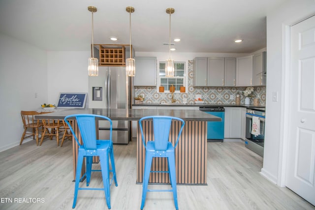 kitchen with light hardwood / wood-style flooring, decorative backsplash, stainless steel appliances, and pendant lighting