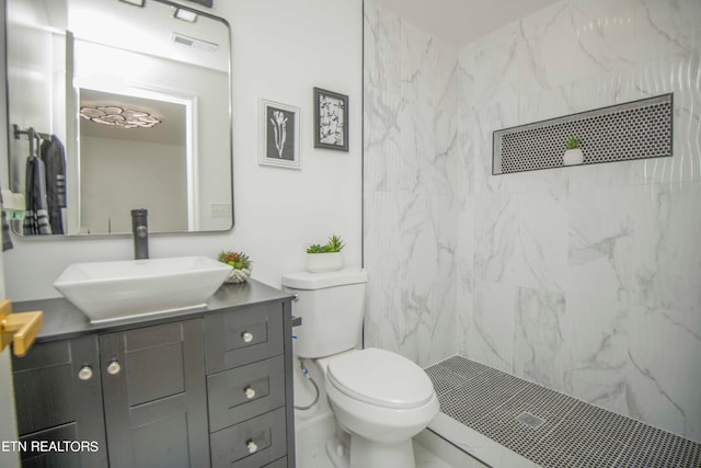 bathroom featuring vanity, tiled shower, and toilet