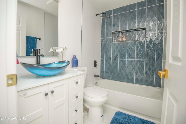 full bathroom featuring tiled shower / bath, vanity, and toilet