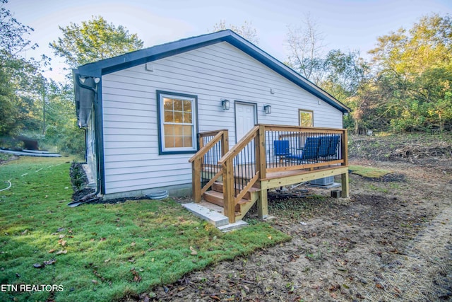 rear view of house featuring a wooden deck and a lawn