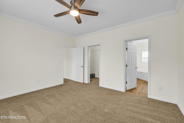 unfurnished bedroom featuring connected bathroom, a closet, a walk in closet, crown molding, and ceiling fan