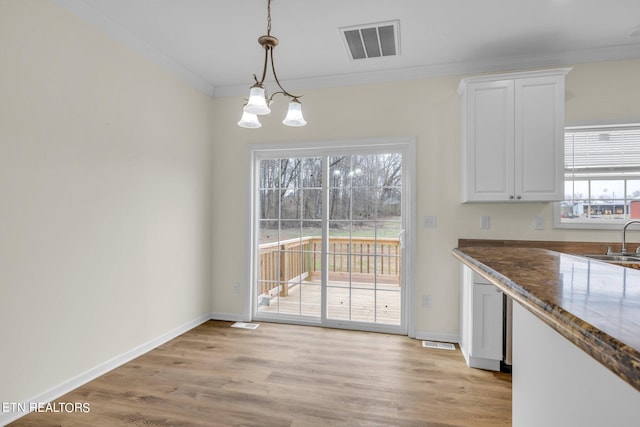 unfurnished dining area featuring ornamental molding, a chandelier, sink, and light wood-type flooring