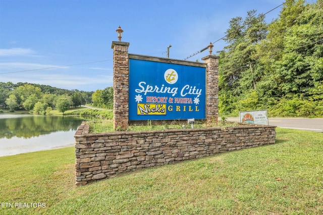 community / neighborhood sign with a water view and a lawn