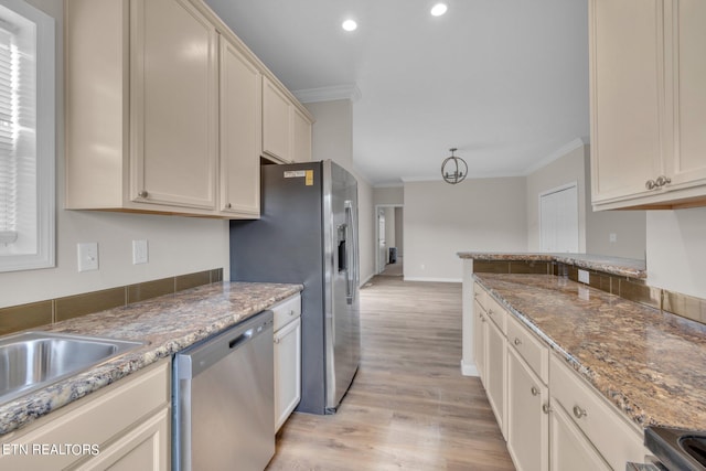 kitchen featuring stone countertops, cream cabinetry, light hardwood / wood-style flooring, crown molding, and appliances with stainless steel finishes