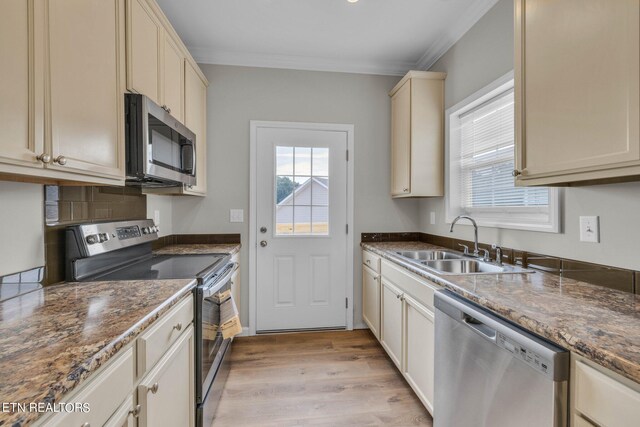 kitchen with cream cabinets, sink, light hardwood / wood-style floors, stainless steel appliances, and crown molding