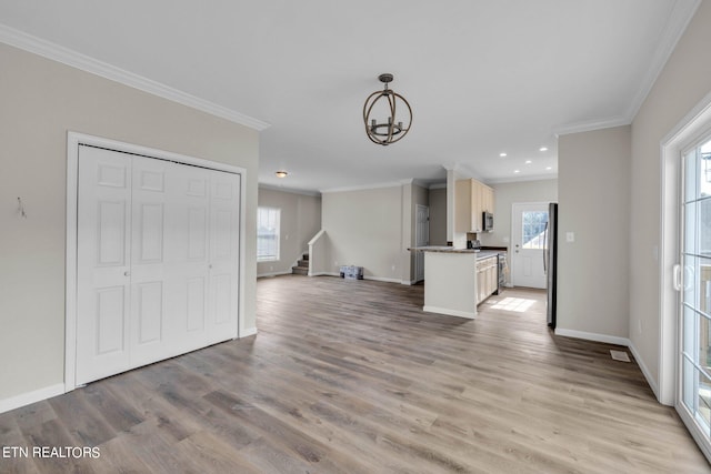 interior space with an inviting chandelier, ornamental molding, and light hardwood / wood-style floors