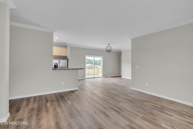 unfurnished living room featuring crown molding, hardwood / wood-style floors, and a chandelier