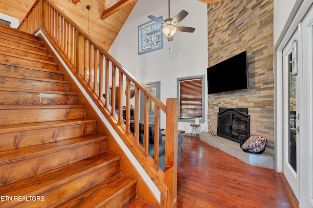 staircase with high vaulted ceiling, hardwood / wood-style flooring, a fireplace, beam ceiling, and wood ceiling