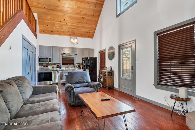 living room with a towering ceiling, dark wood-type flooring, and a notable chandelier