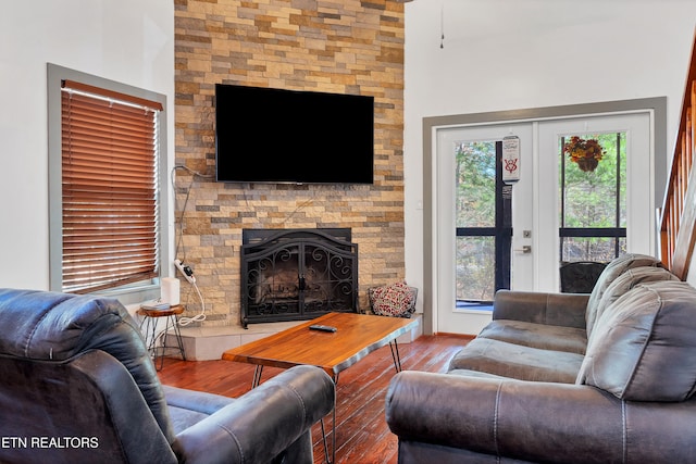 living room featuring hardwood / wood-style flooring, a stone fireplace, and french doors