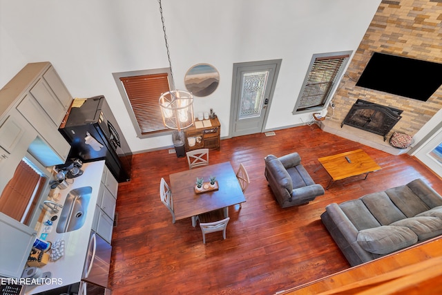 living room with a fireplace, dark hardwood / wood-style flooring, and a towering ceiling