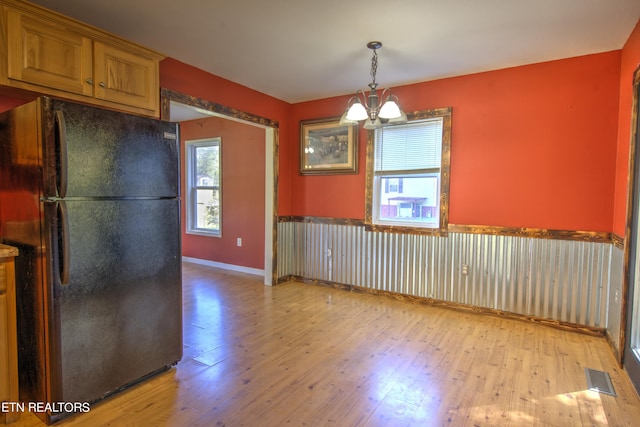 kitchen with light hardwood / wood-style floors, an inviting chandelier, pendant lighting, and black fridge