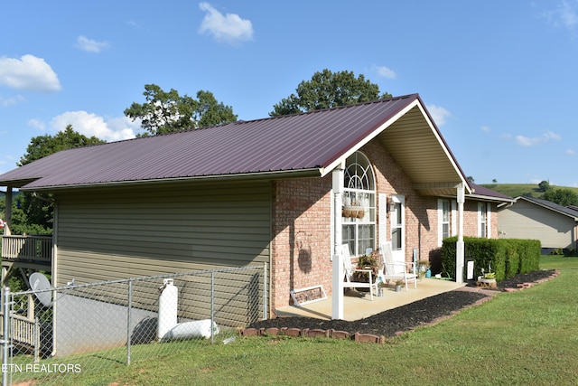 view of side of property with a patio and a lawn