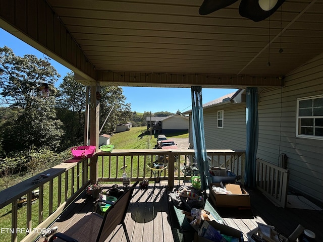 wooden deck featuring a lawn and ceiling fan