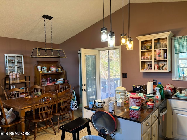 kitchen featuring lofted ceiling, a textured ceiling, decorative light fixtures, and white cabinets