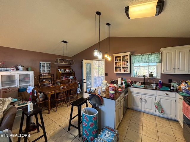 kitchen with sink, hanging light fixtures, white cabinetry, lofted ceiling, and light tile patterned floors