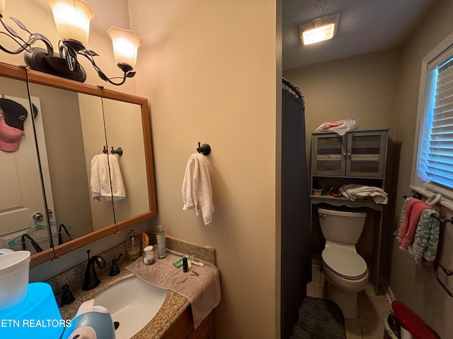 bathroom featuring vanity, a textured ceiling, a healthy amount of sunlight, and toilet