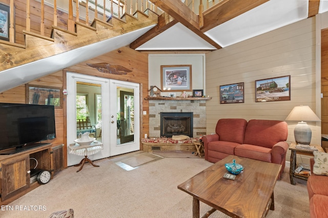 living room featuring wood walls, a fireplace, french doors, lofted ceiling with beams, and light carpet