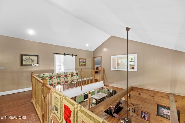 living room with dark wood-type flooring, vaulted ceiling, and a barn door