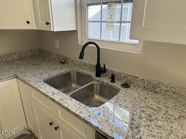 kitchen with white cabinets, sink, and light stone counters