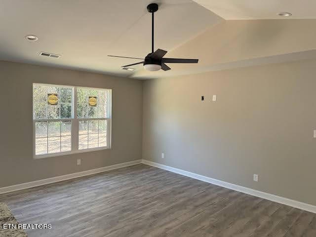 empty room with lofted ceiling, dark hardwood / wood-style floors, and ceiling fan