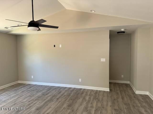 spare room featuring dark wood-type flooring, ceiling fan, and vaulted ceiling