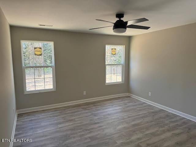 unfurnished room featuring a wealth of natural light, wood-type flooring, and ceiling fan