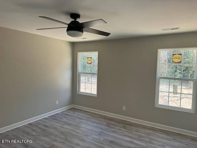 empty room with hardwood / wood-style flooring, a healthy amount of sunlight, and ceiling fan