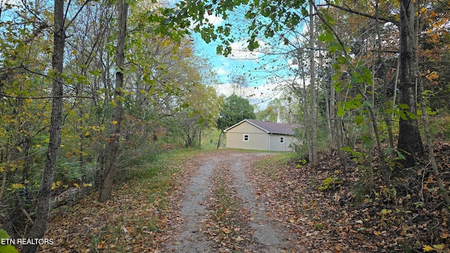 view of side of property with driveway and a view of trees