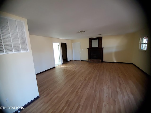 unfurnished room featuring baseboards, wood finished floors, and a fireplace