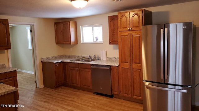 kitchen with a sink, appliances with stainless steel finishes, and brown cabinetry