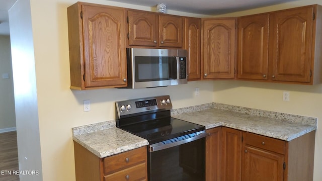 kitchen with brown cabinetry, stainless steel appliances, and light countertops