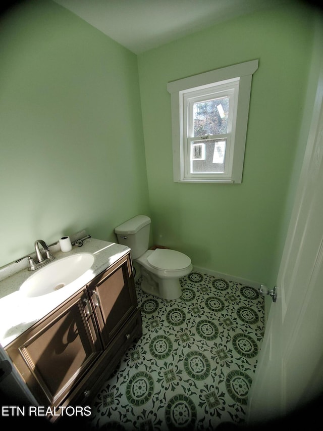 half bath featuring tile patterned flooring, toilet, vanity, and baseboards