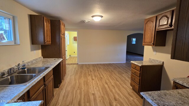 kitchen with visible vents, a sink, arched walkways, light wood-style floors, and light countertops