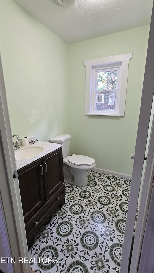 bathroom with tile patterned floors, toilet, a textured ceiling, baseboards, and vanity