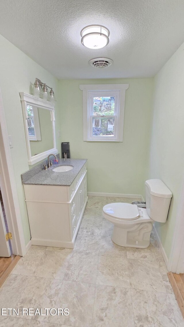 bathroom with vanity, toilet, visible vents, and a textured ceiling