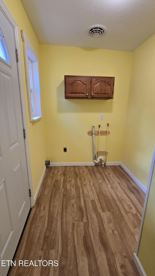 laundry area with wood finished floors, cabinet space, visible vents, and baseboards