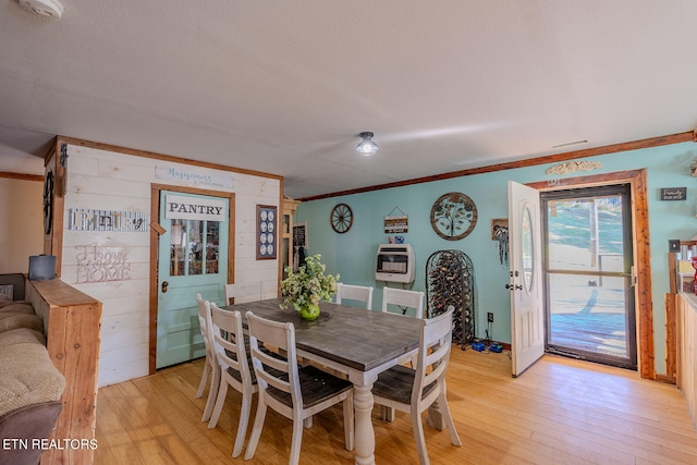 dining area featuring light hardwood / wood-style floors, crown molding, and heating unit