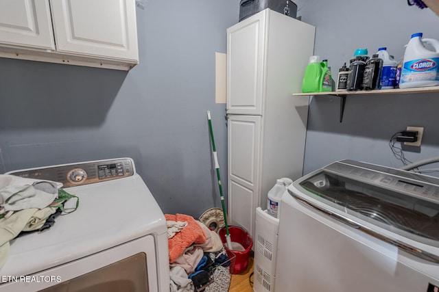 laundry area with washer / dryer, hardwood / wood-style floors, and cabinets