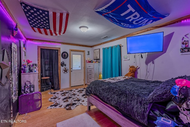 bedroom featuring ornamental molding, a textured ceiling, and hardwood / wood-style flooring