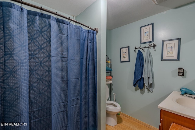 bathroom featuring hardwood / wood-style flooring, toilet, a shower with curtain, vanity, and a textured ceiling