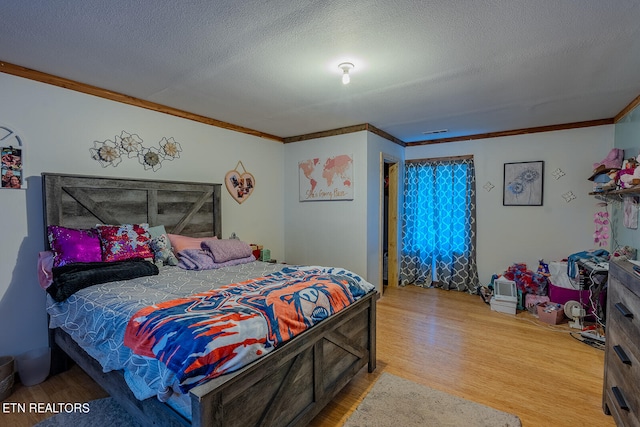 bedroom featuring ornamental molding, a textured ceiling, and wood-type flooring